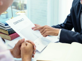 Business professionals review a contract at a desk