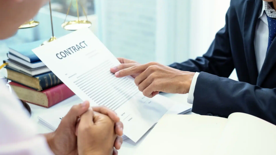 Business professionals review a contract at a desk